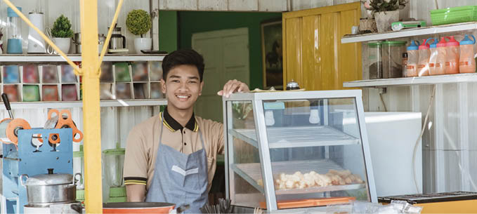 proud young asian man small business owner at his shop made of truck container selling street food