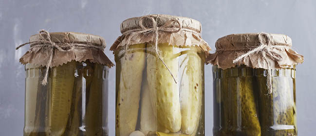 Pickled cucumbers in glass jars on blue background. High quality photo