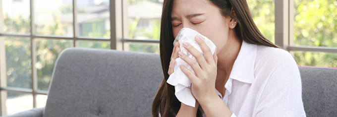 beautiful asian woman sick with the flu have a stuffy nose Hold a tissue to cover your mouth. Prevent the virus from spreading. health care concept